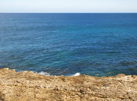 calm blue ocean seen from a clifftop with neutral sky