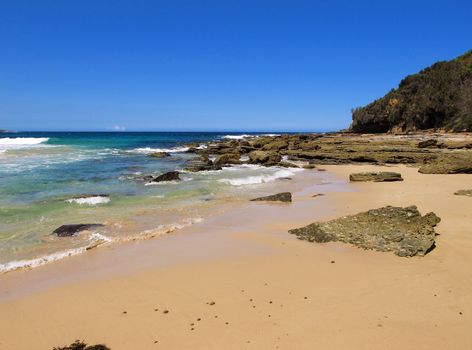 perfect natural beach with sand, stones, cliff and blue sky