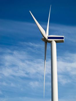 wind turbine seen from the side against blue sky with light clouds