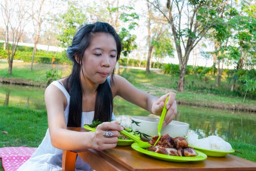 Asian Thai girl is eating beside swamp.