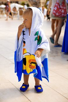 little boy is wrapped in towel stands in surroundings people