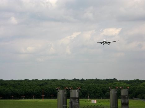 Landing airplane with cloudy sky and forest in background
