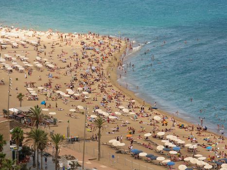 crowded city beach of barcelona seen from the port vell aerial tramway