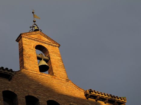 church bell on open belfry tower in warm sunlight