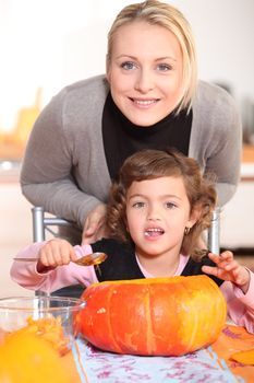 Mother and daughter carving jack-o-lanterns