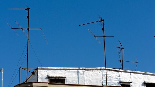 television antennas on the roof of a white spanish house