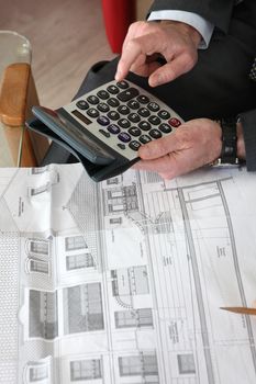 Architect sat with blueprints and calculator