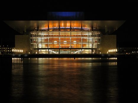 the new opera house of copenhagen at night seen from the other side of the harbor