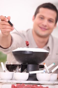 30 years old man eating meat fondue