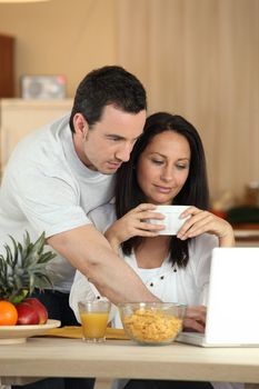 Couple eating breakfast in front of laptop