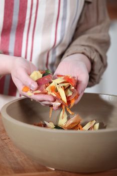 Woman gathering vegetable peeling in a bowl