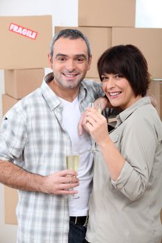 Couple drinking champagne in front of a pile of cardboard boxes