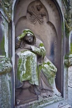 old statue of a grieving woman on a cemetery