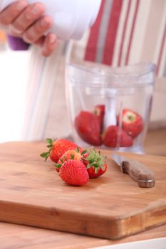 Woman putting strawberries in a blender