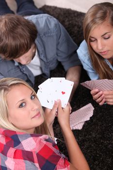 Young people playing cards with a girl showing the winning hand
