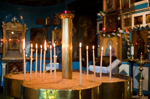 Candles inside the sandpool with jesus and apostles siluette in a church