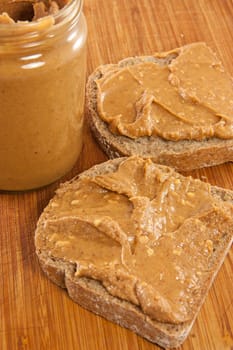 Picture of two slices of bread with peanut butter and a jar of peanut butter