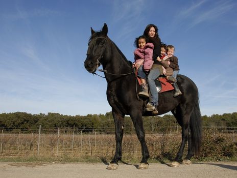 children and mother and a black stallion on a street