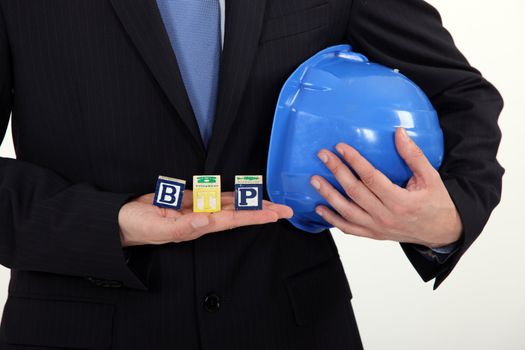 Businessman holding a hard hat and letter blocks