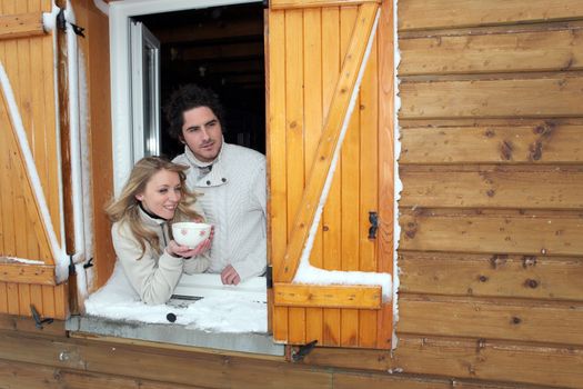 Couple looking out of their winter cabin