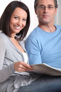 Couple reading through magazine together on sofa