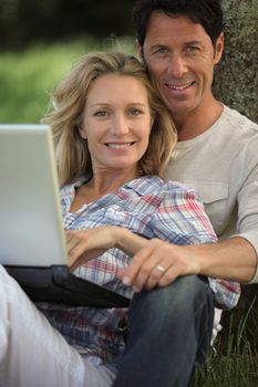 happy couple outdoors with laptop
