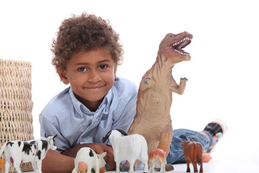 Young boy playing with a toy dinosaur and collection of domestic animals