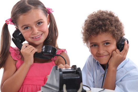 two children using an old telephone