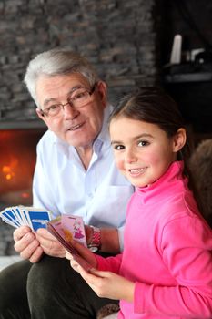 Old man playing card game with his granddaughter