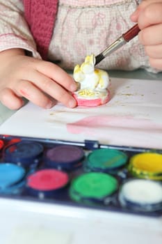 Little girl painting figurine