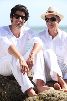 Father and son sat on rock at the beach