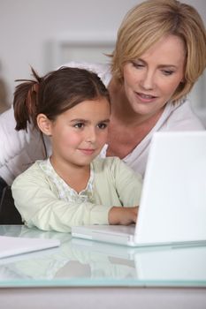 mother showing her little girl how to use the laptop