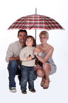 Young family sheltering under an umbrella