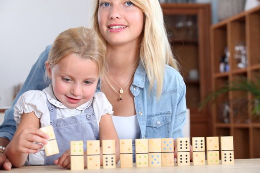A mother and daughter playing with dominos.
