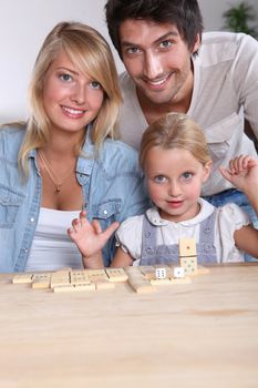 Parents and daughter playing dominoes