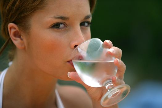 Brunette drinking glass of water outdoors