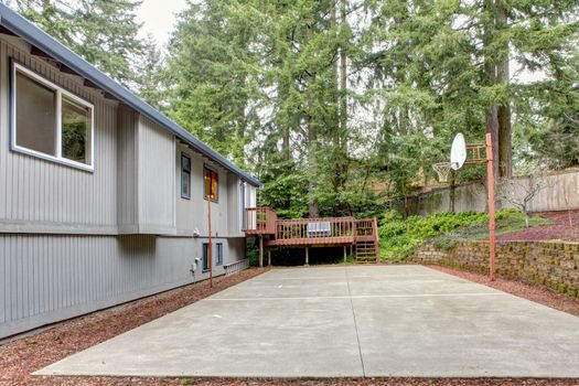 Grey house with backyard with basket ball area.