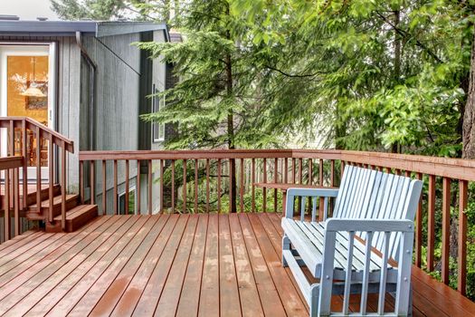 Small deck with blue chair and grey house.