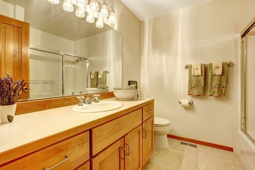 Simple white bathroom with wood cabinets,