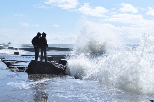 Sea waves breaking on concrete port with spray