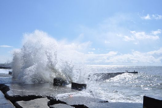 Sea waves breaking on concrete port with spray