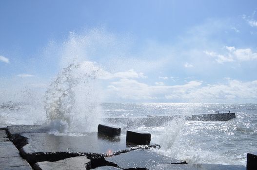 Sea waves breaking on concrete port with spray