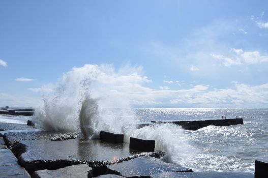 Sea waves breaking on concrete port with spray