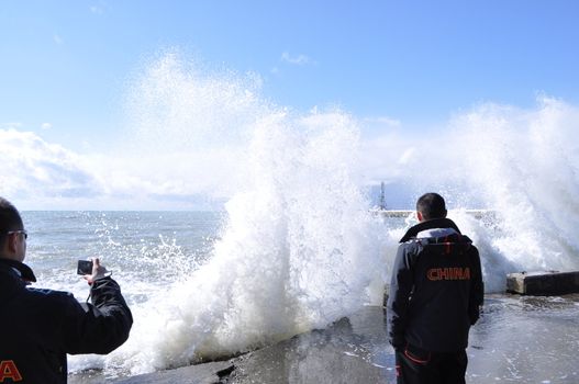 Sea waves breaking on concrete port with spray