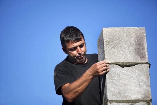 mason erecting a stone block wall