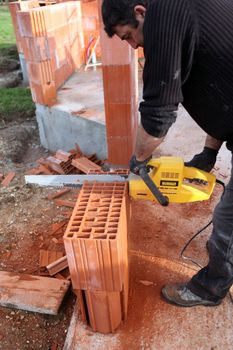 Man using a chainsaw to cut through a brick