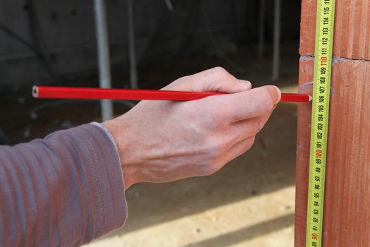 Man measuring brick wall