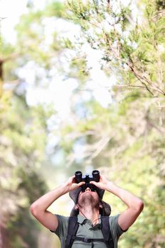 Binoculars - man hiker looking up at copy space during outdoors hiking trip.