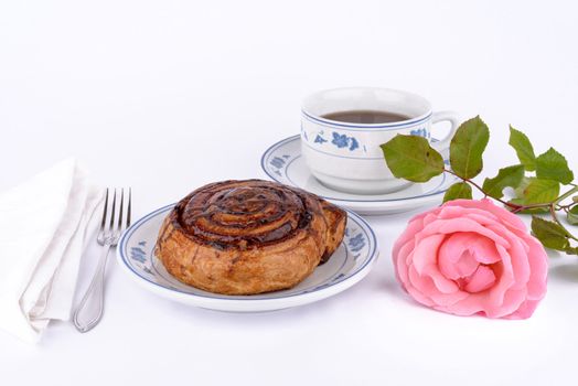 Closeup of cup of tea with cake and roses