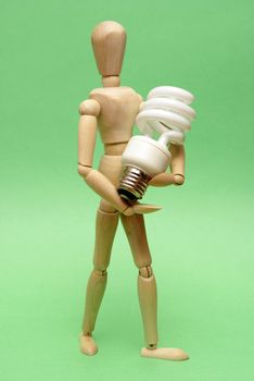 A wooden guy holds onto a modern cfl lightbulb for many ecological concepts.